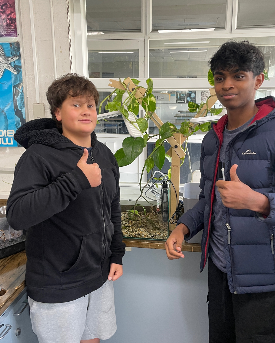Two students giving a thumbs up beside their classroom Farmwall system
